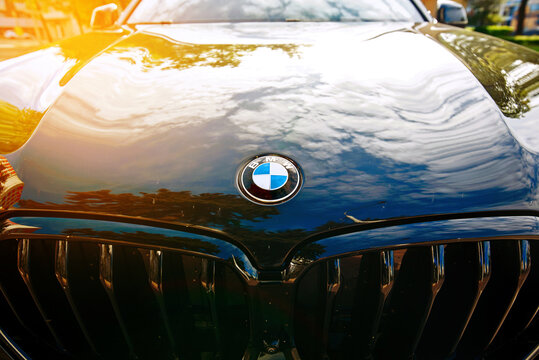 Minsk, Belarus. May 13, 2024. BMW logo on black car hood and chrome grille closeup, wide angle view on front body exterior. BMW X5, German automobile exterior design
