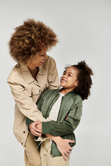 A curly African American mother and daughter in stylish clothes embrace in a heartwarming hug...