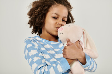 Young girl in pajamas affectionately embraces a stuffed animal