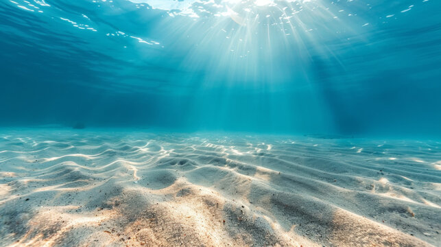 Underwater view of rippling sandy ocean floor bathed in beautiful sunlight beams, creating a serene and tranquil marine seascape.