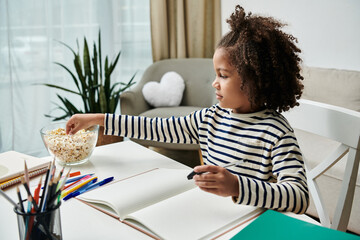 A little girl joyfully sits at a table, enjoying a bowl of popcorn