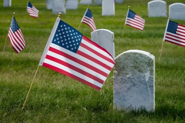 American flag waving next to tombstone in grassy field, creating solemn cemetery scene.