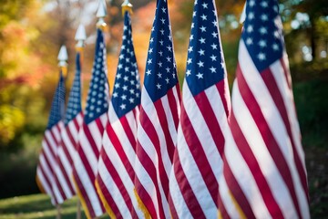 Row of colorful American flags against autumn trees, symbolizing patriotism and reflection.