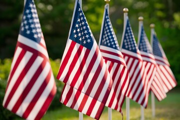 Patriotic row of flags fluttering in the breeze against lush greenery backdrop.