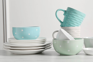 Beautiful ceramic dishware and cups on white marble table