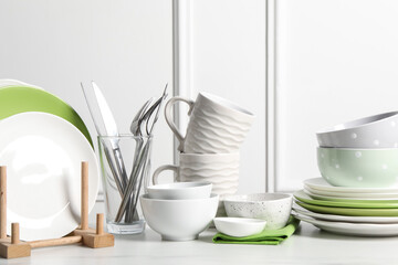 Beautiful ceramic dishware, cups and cutlery on white marble table