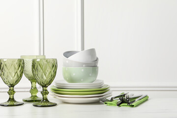 Beautiful ceramic dishware, glasses and cutlery on white marble table. Space for text