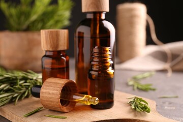 Essential oil in bottles, dropper and rosemary on table, closeup