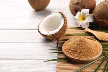 Coconut sugar, palm leaves, fruits and bamboo mat on wooden rustic table, closeup. Space for text