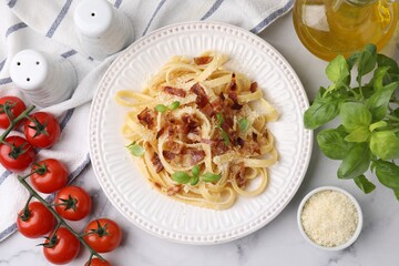 Tasty pasta with bacon and basil on white marble table, flat lay