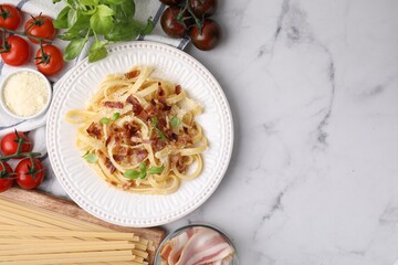 Tasty pasta with bacon and basil on white marble table, flat lay. Space for text