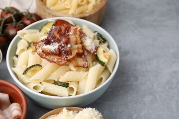 Tasty pasta with bacon and cheese on grey table, space for text