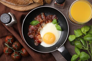 Fried egg and bacon served on brown table, top view