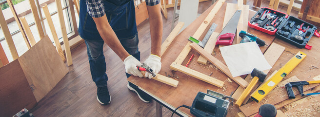 Banner DIY craftsperson asian man working wood heap carpenter objects woodwork desk. Banner Architect man hands ruler measure home improvement. Wood carpenter construction workshop with copy space