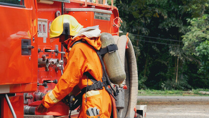 Fireman prepare equipment fighting extinguisher at fire engine truck. Firefighter fighting with...