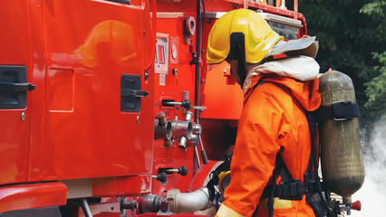 Fireman prepare equipment fighting extinguisher at fire engine truck. Firefighter fighting with...