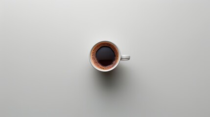 Top-down shot of a white cup filled with black coffee on a light grey background, emphasizing minimalism and simplicity.
