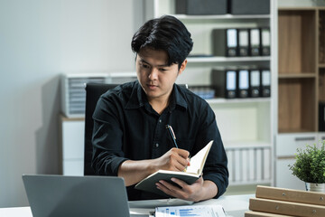 Young employee using computer working online, doing searching, taking notes, watching business...