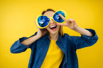 cheerful woman blogger influencer on rock-and-roll party show v-sign symbol over yellow background