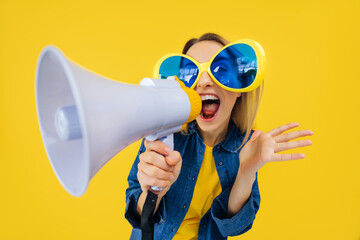 Active woman in comic glasses holding loudspeaker and making advertisement while laughing....