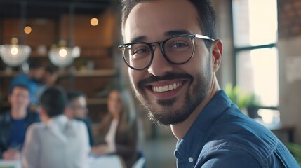 Obraz premium Portrait of happy millennial male business owner in modern office Businessman wearing glasses smiling and looking at camera Busy diverse team working in background Leadership concept H : Generative AI