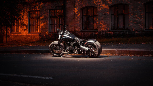 Night long exposure shot of custom bike based on Harley-Davidson Fat Boy model. Black motorcycle parked at night near an old building. Kyiv, Ukraine - September 20 2014.
