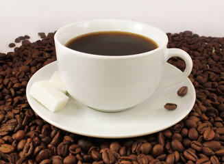 A cup of americano standing on coffee beans.