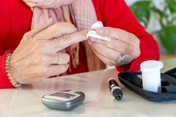 Detail of steril sterilizing her finger in order to test sugar level on with glucose monitoring kit