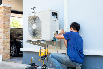 Male technician installing outdoor unit of air conditioner  to cool the household in the summer....