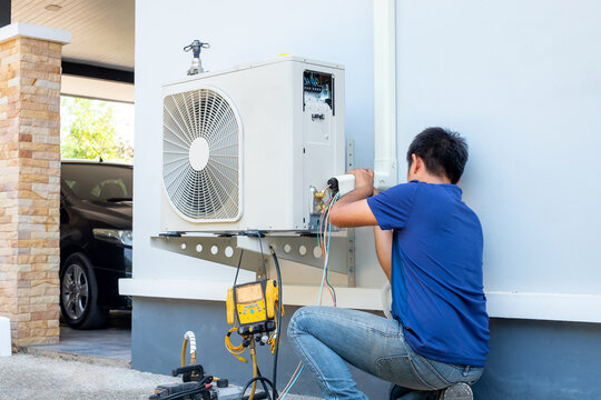 Male technician installing outdoor unit of air conditioner to cool the household in the summer. air compressor, electronic, hot summer, high temperature, Tropical countries