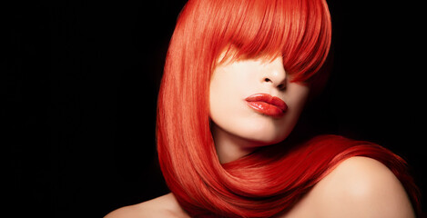 Beautiful model with healthy dyed red hair posing against black background