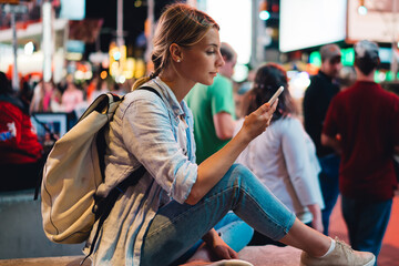 Young woman reading message on mobile phone using internet in roaming during trip to New York,...