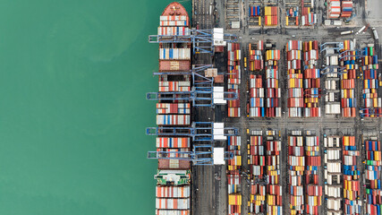 top down view from drone, crane lift container into the transport ship in commercial port, shipping...
