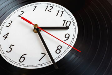 Clock vinyl record plate, arrow, backward time close-up.