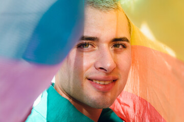 Happy Handsome Gay Latin Man looking at camera under the pride flag