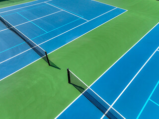 Aerial, drone, photo of new outdoor blue tennis court with white lines combined with light blue...