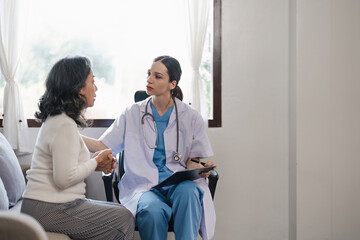 Doctor consulting with senior woman on sofa in home. Healthcare and patient support concept