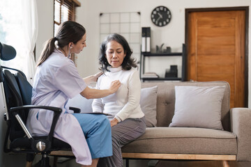 Doctor examining senior woman on sofa in home. Healthcare and physical checkup concept