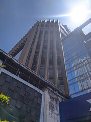 Obraz premium Skyscraper glass facades on a bright sunny day with sunbeams in the blue sky. Bottom up view