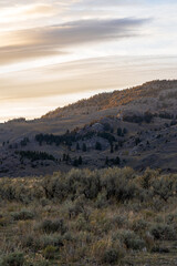 Fototapeta premium Sunset in the Lamar Valley in Yellowstone National Park in Montana and Wyoming on a beautiful fall evening. Sun sets over the mountains and sagebrush with a colorful sky illuminating the landscape.