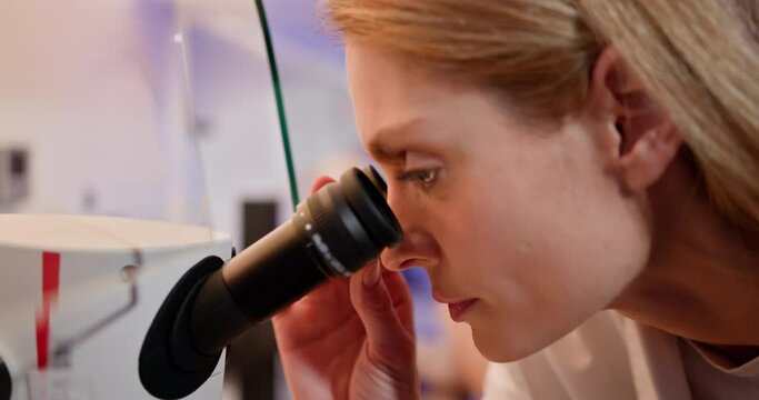 An embryologist performing an artificial fertilization of a human egg using a microscope in a laboratory setting. Embryologist Performing IVF Procedure in Laboratory