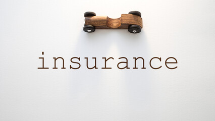 A wooden toy car is placed above the word insurance on a minimalist white background, symbolizing...