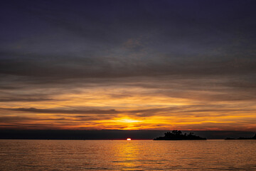 Obraz premium sunset over the sea with bright sun and dark clouds