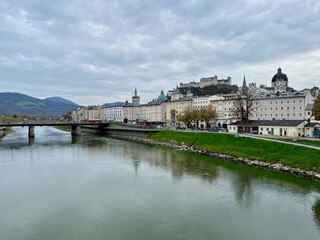 Fototapeta premium Marko-Feingold-Steg bridge above the Salzach River in Salzburg, Austria, showcasing its modern design and scenic surroundings with the city in the background.