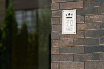 Intercom with camera and keyboard on the wall at the entrance to an office space or residential apartment building. Entrance doorbell in a multi-apartment building, with a video surveillance camera.