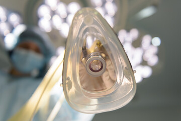 Anesthesiologist puts an oxygen mask on the patient.  Preparing for surgery. The doctor administers inhalation anesthesia using an anesthesia machine before intubation. Emergency and first aid concept