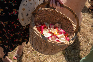 Un panier en osier rempli de p&eacute;tales de fleurs est tenu par une demoiselle d'honneur &agrave; un mariage.