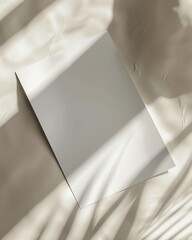 Blank white paper on a white fabric background with natural light