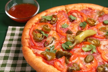 Delicious pizza Diablo and sauce on green wooden table, closeup