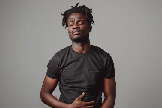 A man with long dreadlocks stands confidently in front of a gray backdrop